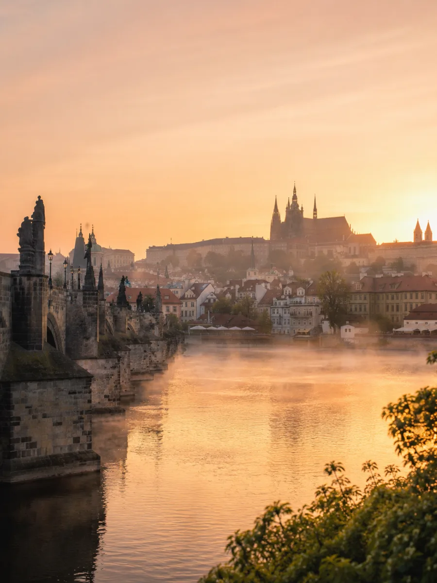 El Puente de Carlos y el castillo de Praga al amanecer con niebla