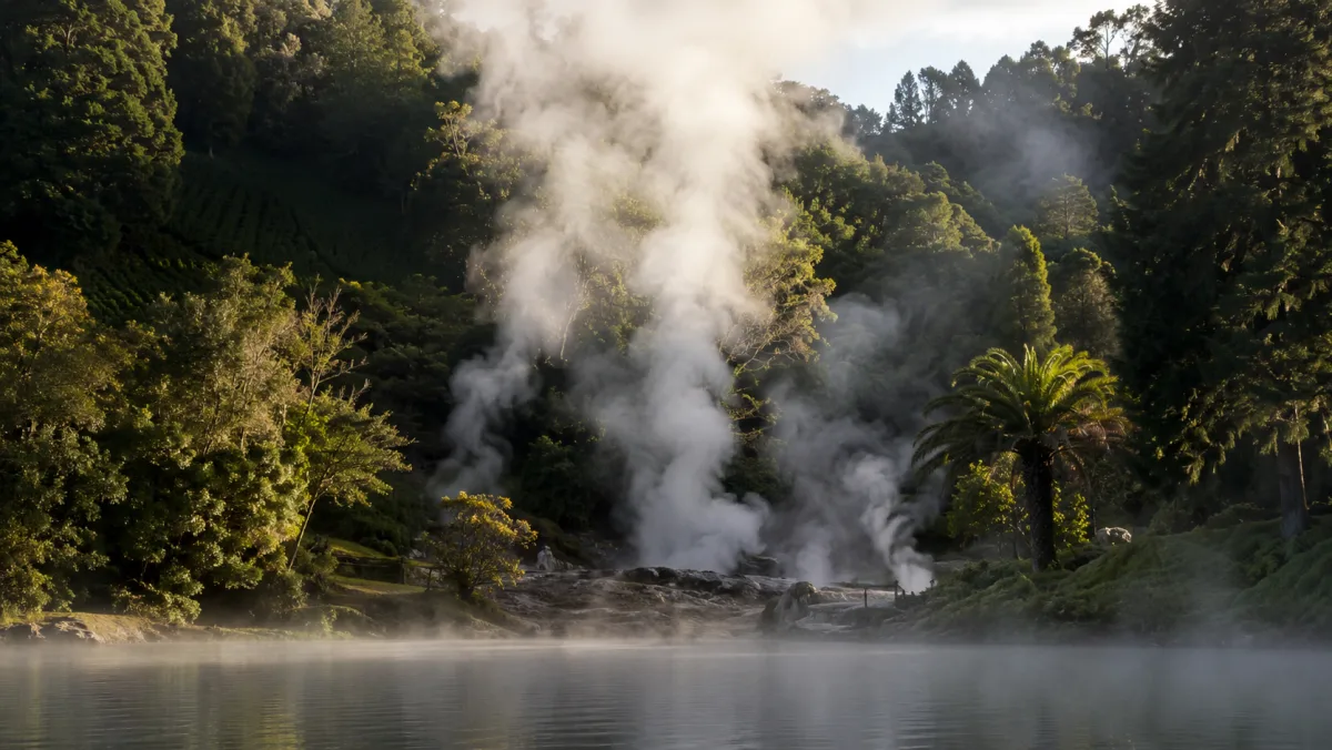 Calderas humeantes al borde del lago de Furnas con vapor blanco subiendo entre vegetación subtropical densa a primera hora de la mañana, São Miguel, Azores