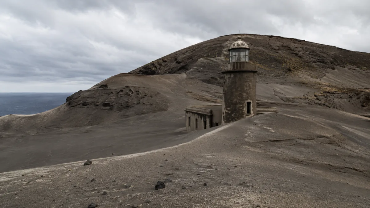 El viejo faro de los Capelinhos medio enterrado en ceniza volcánica gris, en el paisaje lunar del volcán, isla de Faial, Azores