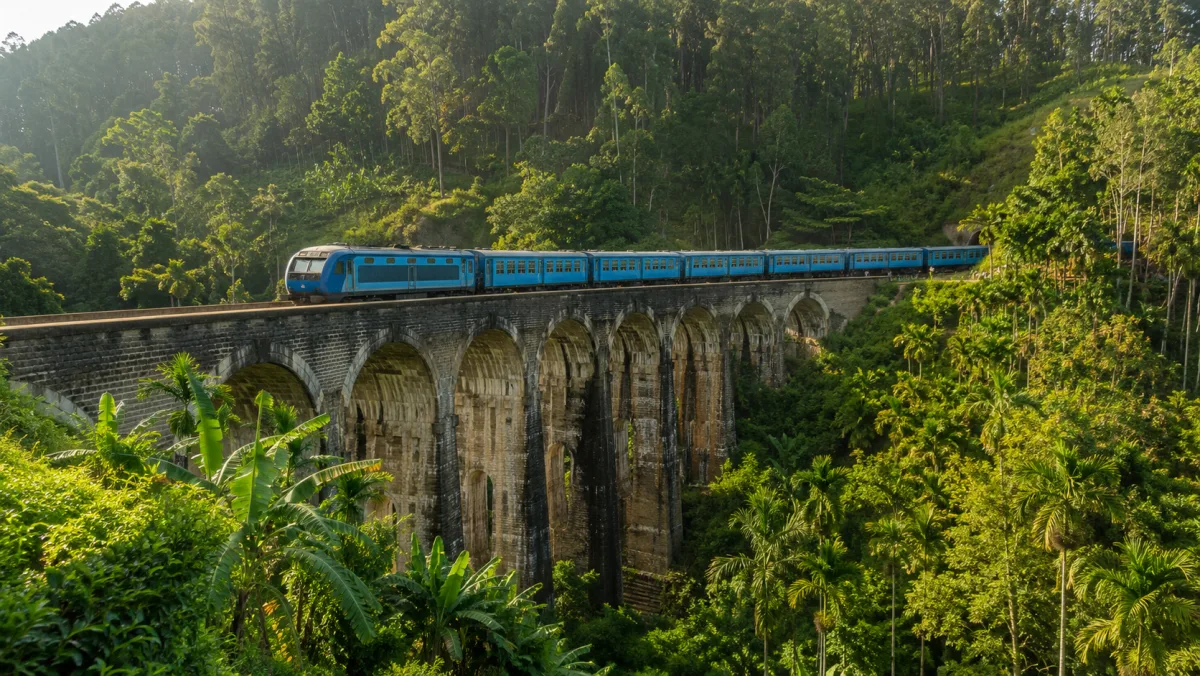 Un tren azul cruzando el puente de los Nueve Arcos (Nine Arch Bridge) de Ella entre selva tropical densa y palmeras, Sri Lanka